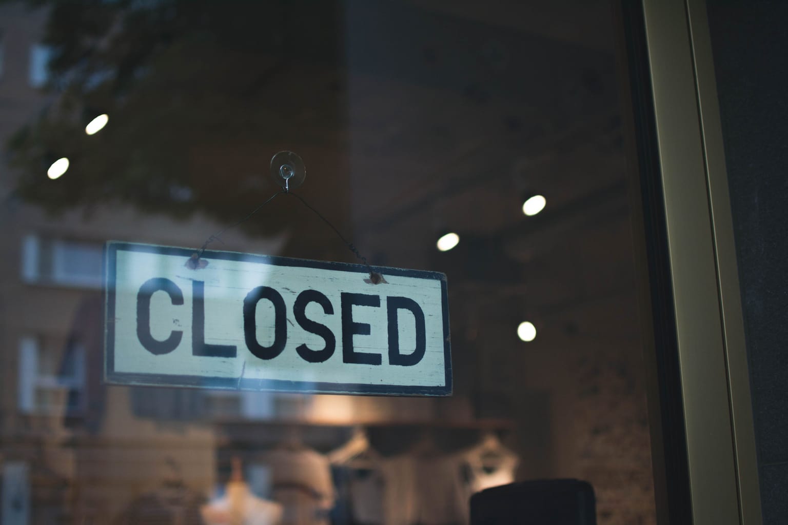 A closed sign hanging in a shop window at night