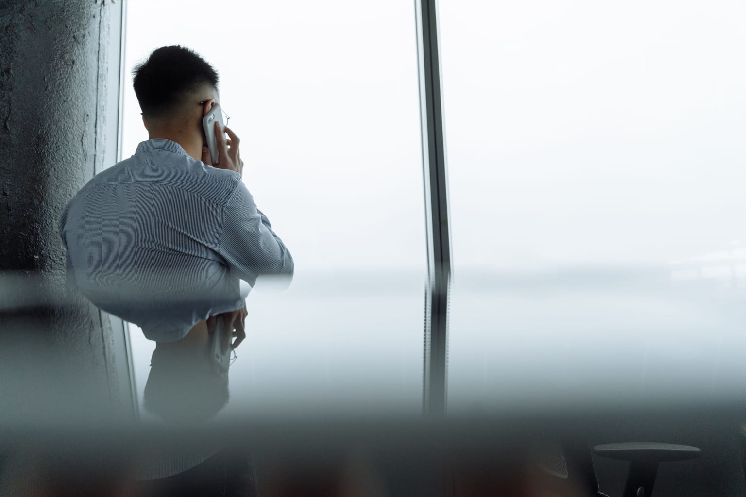 A man turned away from the room, taking a private phone call by a window