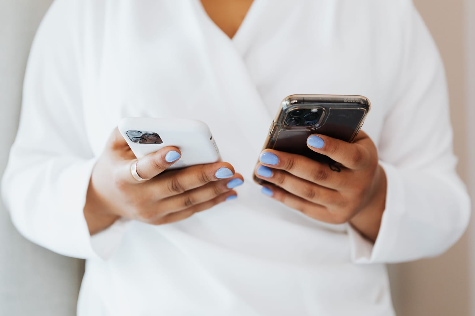 A person holding two phones, one in each hand