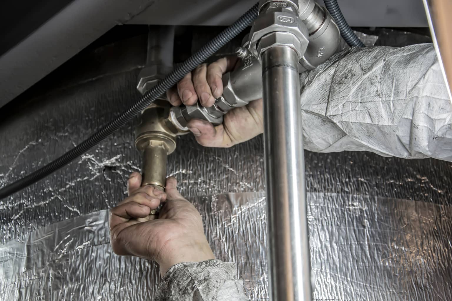 Cost of missed calls for a service business: a plumber's hands fitting a pipe, both of them busy