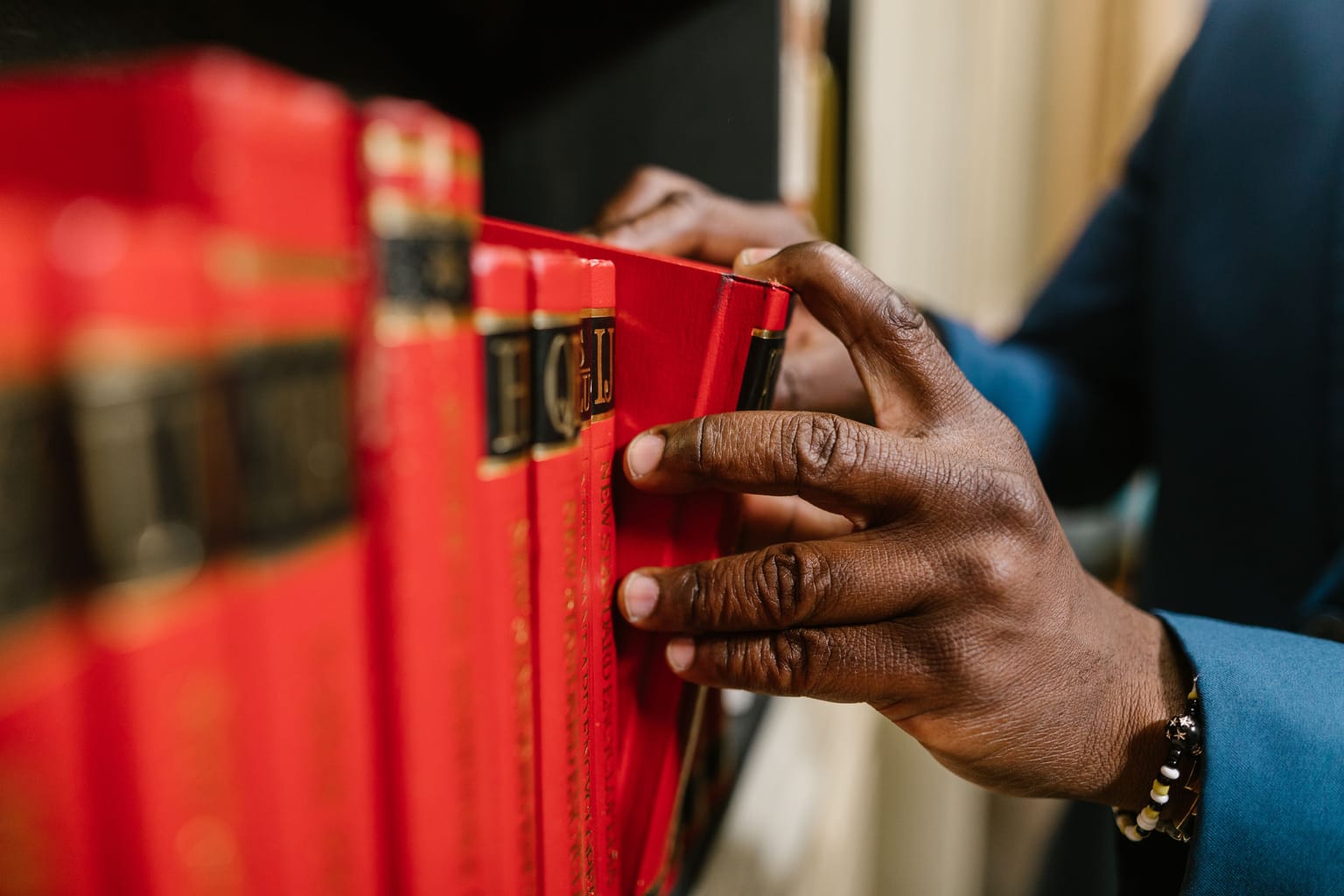A hand taking a red law book down from a shelf
