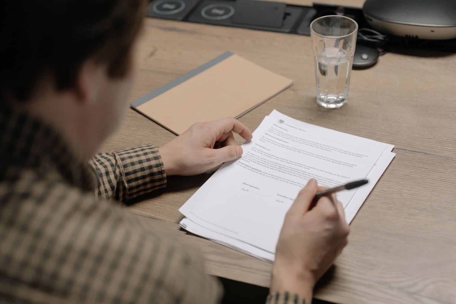 A man reading through an agreement with a pen in hand before signing