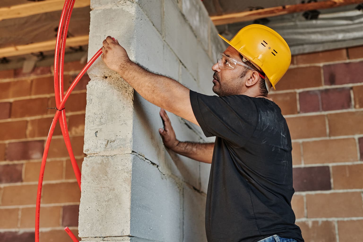 How to answer business calls when busy on a job: an electrician in a hard hat running cable along a wall with both hands