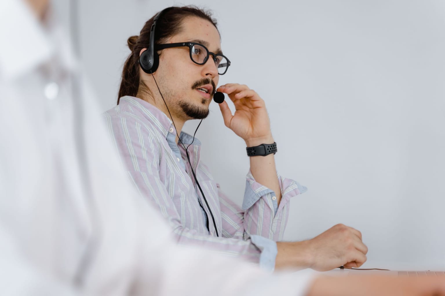 A man in a headset answering a call at a desk