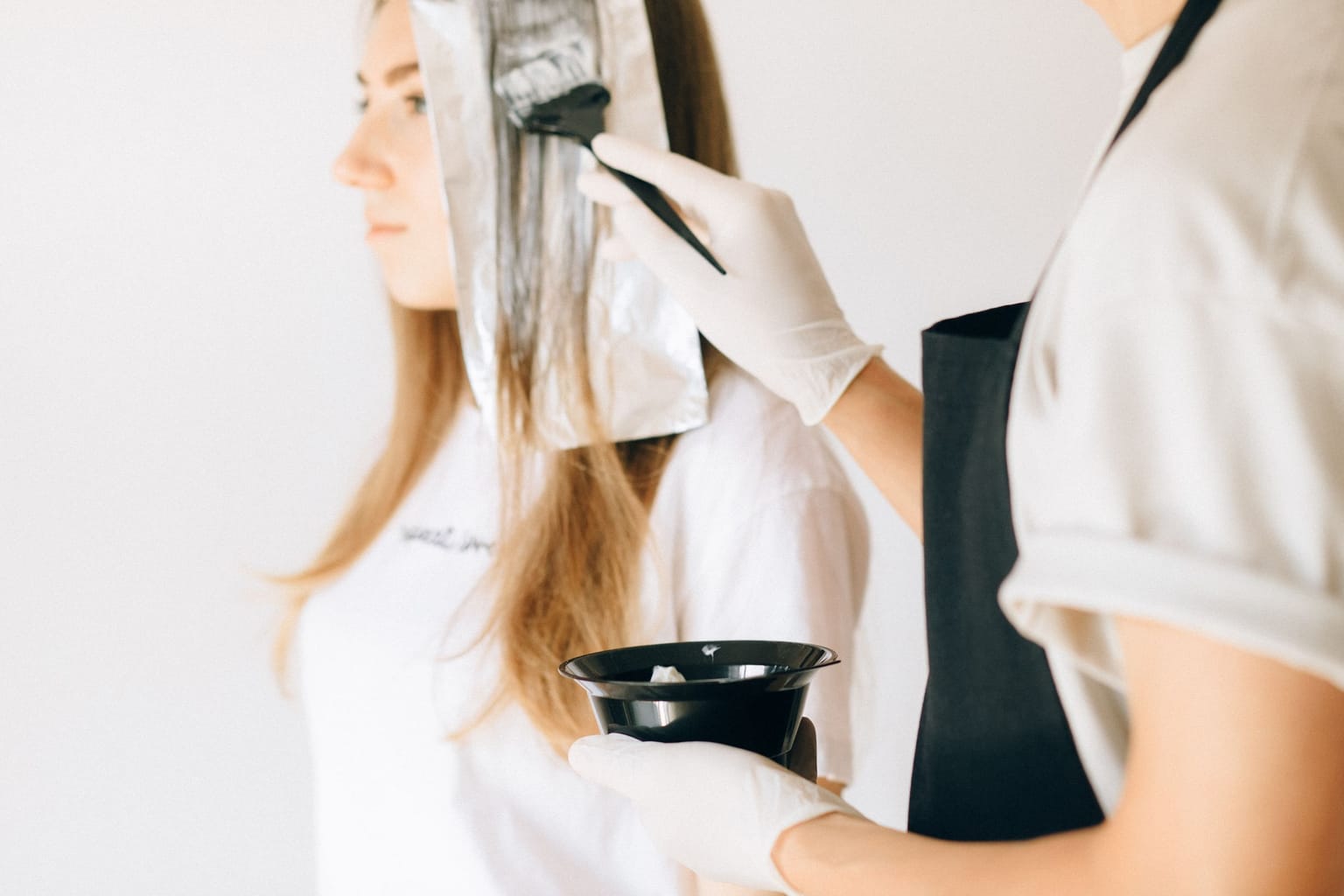 A colourist applying hair colour to a client's hair with a brush