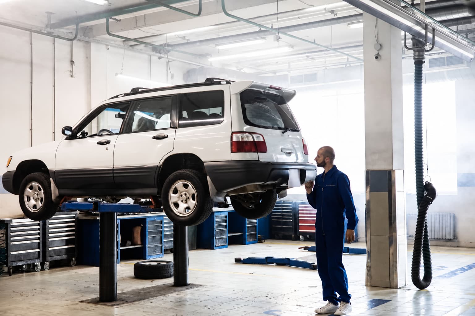 Should mechanics give quotes over the phone: a mechanic looking over an SUV raised on a lift in the service bay