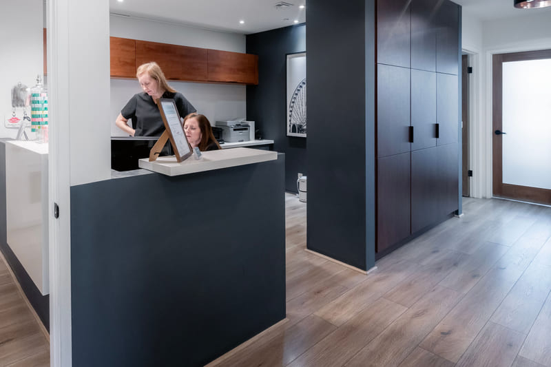 Two members of staff at work behind the front desk of a dental office.