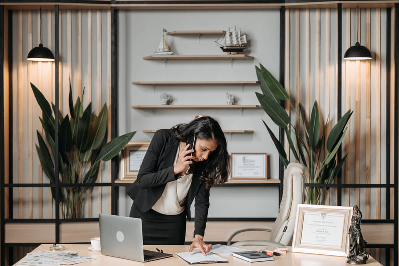 A lawyer on a phone call leaning over her desk to read a document.